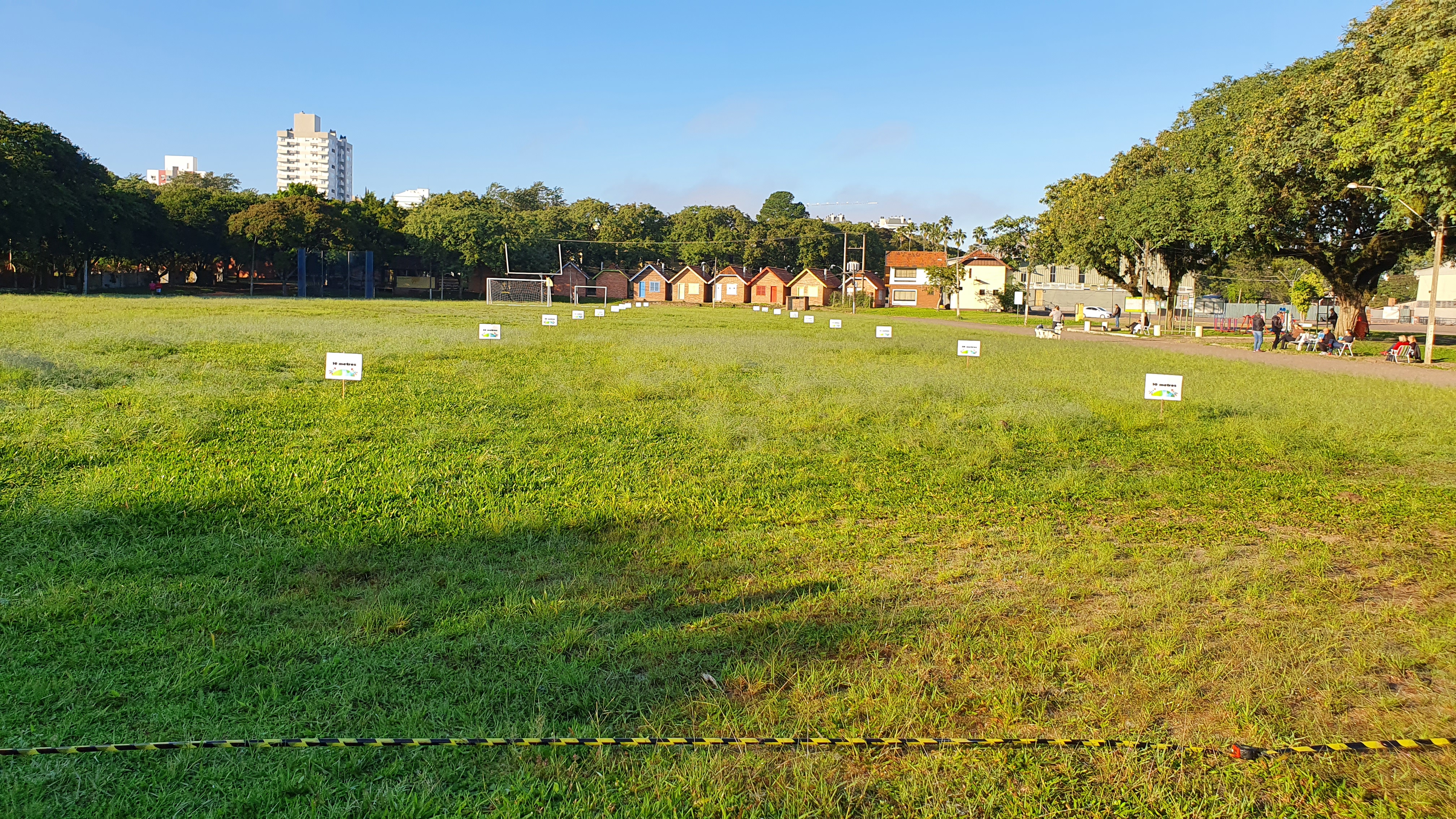 Foto de um gramado verde com diversas plaquinhas enfileiradas, cada uma marcando uma distância de dez em dez metros.