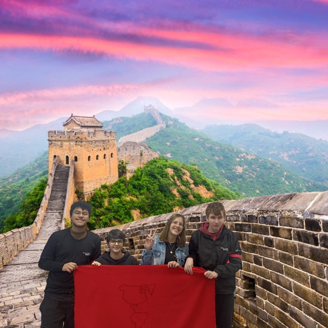 4 integrantes da equipe apontando para a muralha da China, e segurando a bandeira da equipe vermelha.