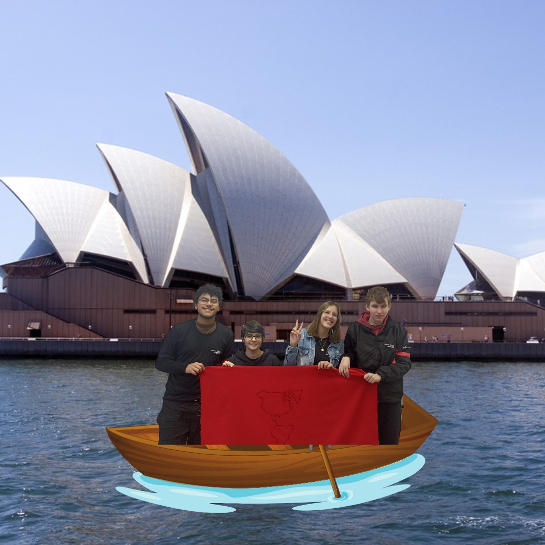 4 integrantes da equipe apontando para a Sydney Opera House, e segurando a bandeira da equipe vermelha.